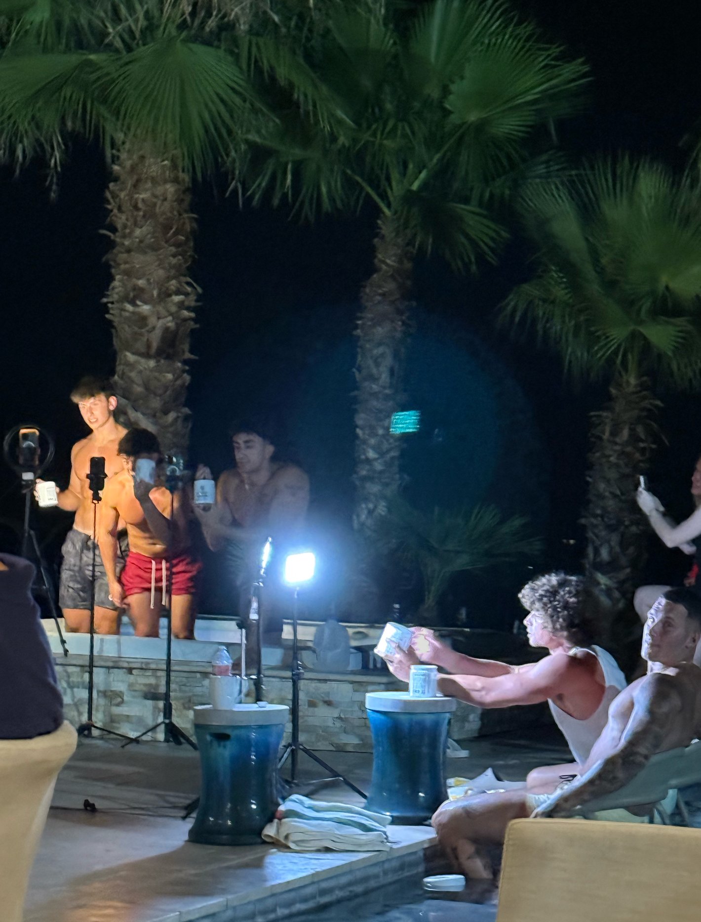 Behind the scenes of an Arizona content shoot at night, creators filming with ring lights and microphones around a pool
